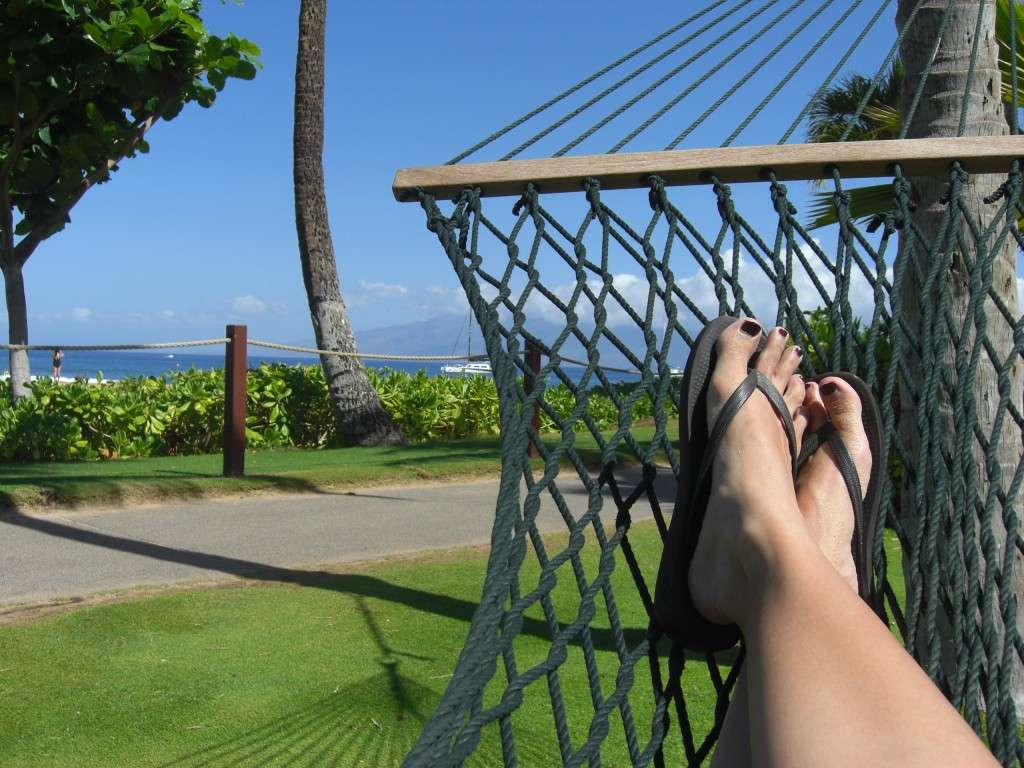 The view from a hammock in kaanapali beach on Maui with palm tree and ocean in the background along with the island of Lanai.