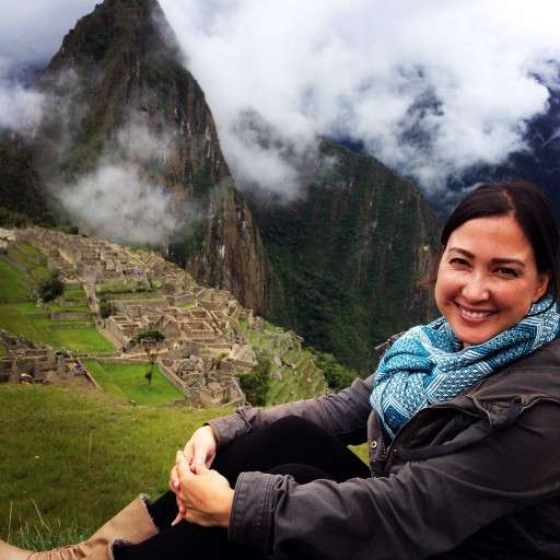 Malia sits in the foreground with the mountains and ancient city of Machu Picchu in the background with clouds shrouding the top peaks.