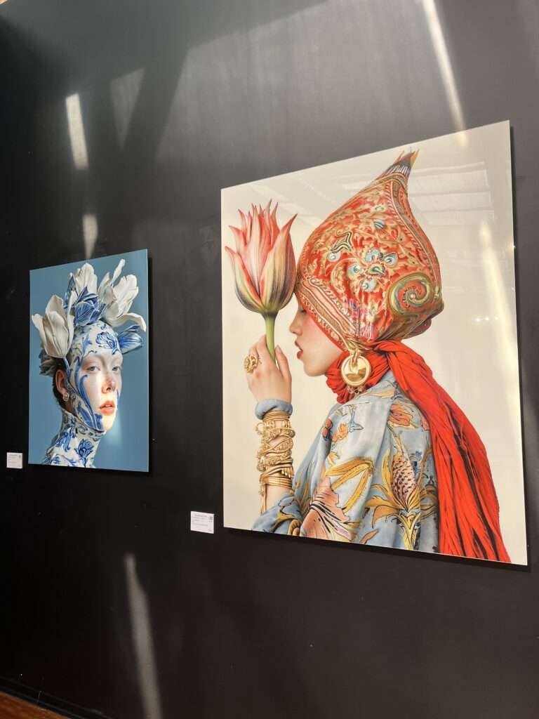 Art gallery display featuring two paintings: on the left, a woman with a blue floral headdress, and on the right, a figure adorned with a red, ornate headpiece and matching attire, both infused with botanical elements. Taken at the Tulipomania Exhibit at the Istanbul Tulip Museum in Emirgan, April 2024.