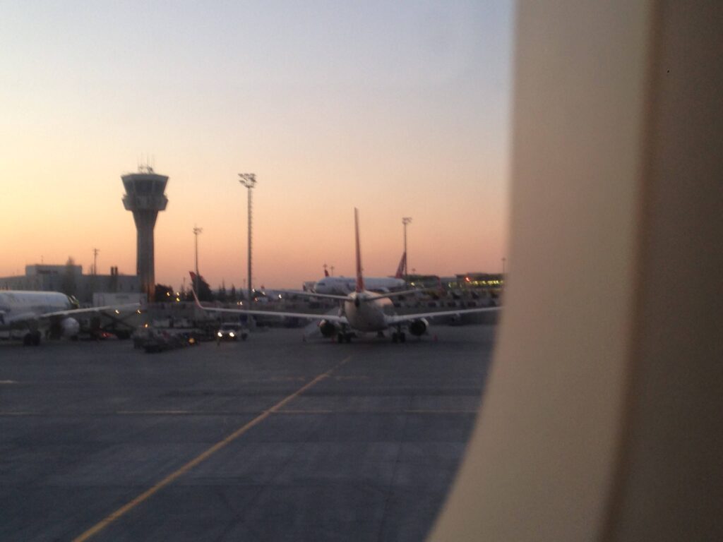 View out of an airplane window - sunrise at LAX with the flight tower and a half dozen planes on the tarmac