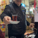 a man holding a tea glass of steaming tea in Eminonu during the Culinary Secrets of the Old City food tour in Istanbul with Culinary Backstreets