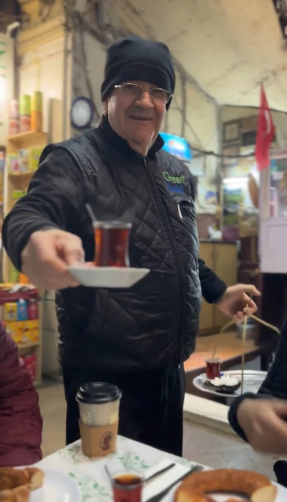 a man holding a tea glass of steaming tea in Eminonu during the Culinary Secrets of the Old City food tour in Istanbul with Culinary Backstreets