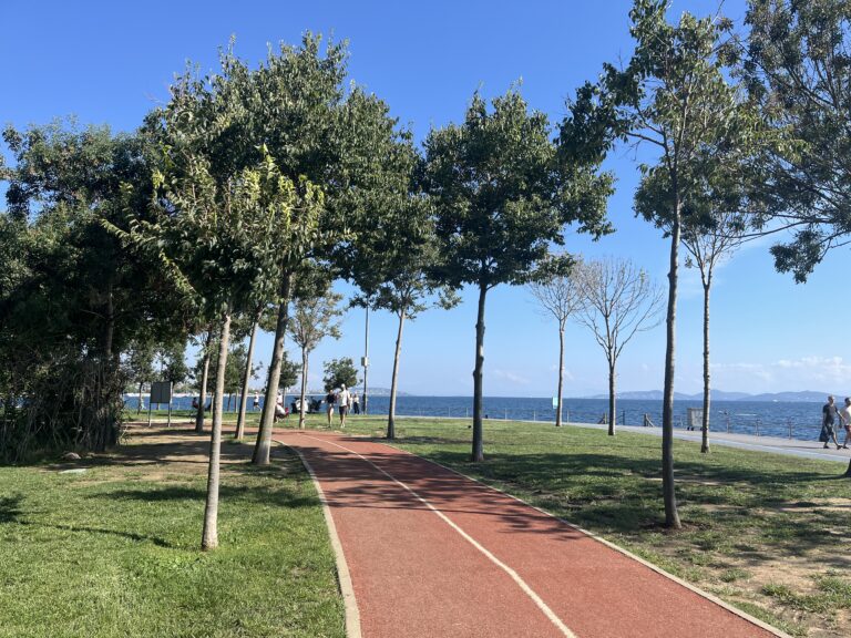 A seaside walking path in Caddebostan on the Asian Side of Istanbul has two tree-lined lanes for bikers and a promenade along the seaside for walkers and runners. green grass and blue skies show off the fresh air.