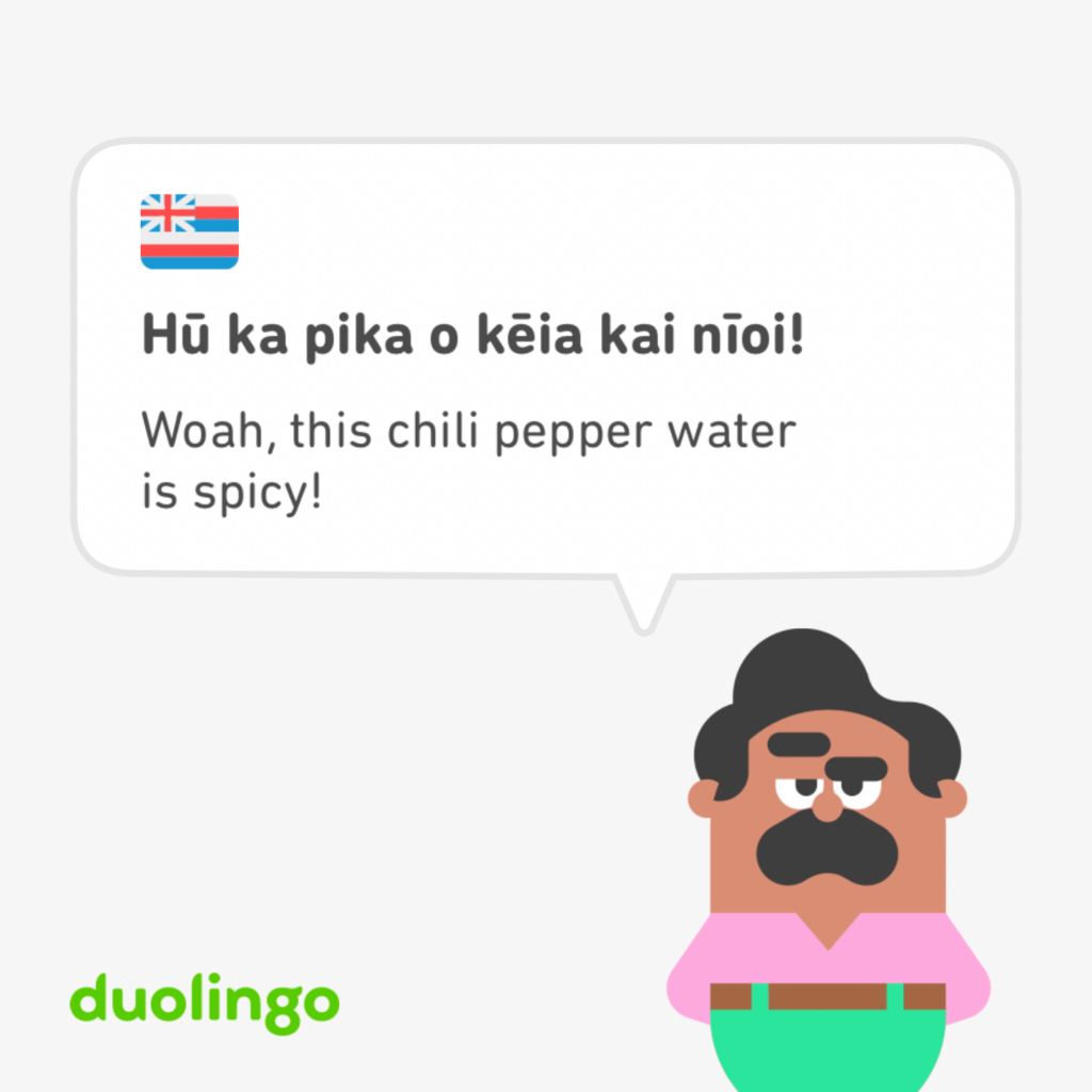 Duolingo card of Hawaiian language with a Hawaiian flag icon followed by the phrase "hu ka pika o keia Kai nioi!" and the English translation, "Woah, this chili pepper water is spicy!" Duolingo is saving endangered languages like Olelo Hawaii, Hawaiian Language.