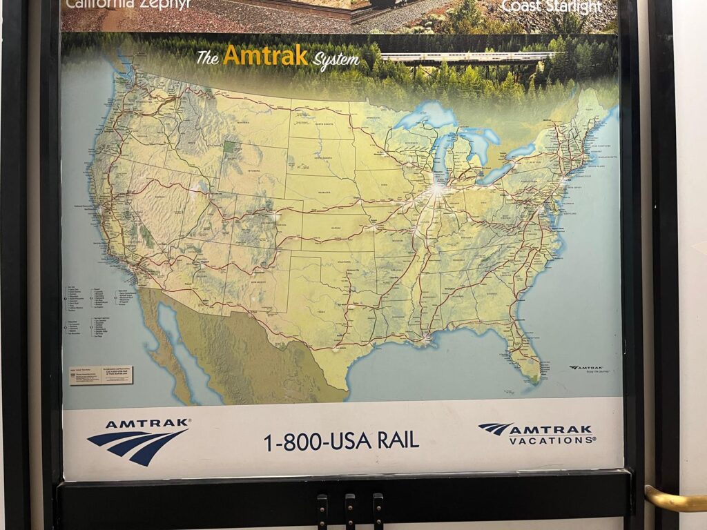 Large Amtrak route map displayed on a station wall showing passenger rail routes across the United States. The map helps readers visualize the nationwide network discussed in the Amtrak FAQs.
