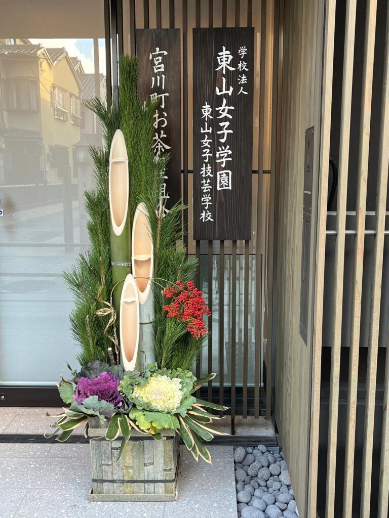 Kyoto was full of kadomatsu, tall new years arrangements made with three stalks of bamboo and pine branches, decorated with purple and white cabbages and red berries, placed next to a doorway
